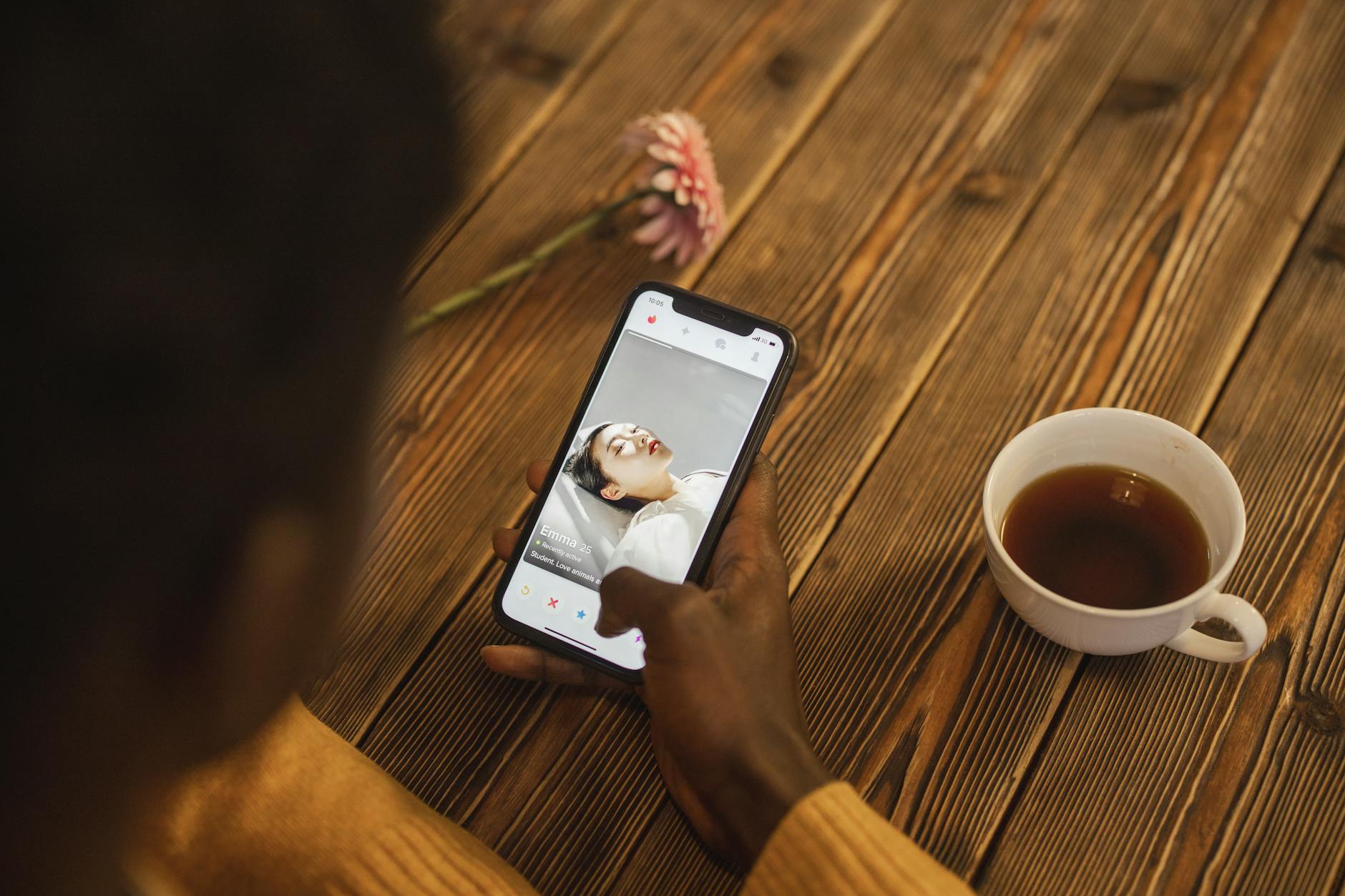 Najczęstsze kłamstwa w profilach: jak je wyłapać bez bycia podejrzliwą Osoba przeglądająca aplikację randkową na smartfonie przy filiżance herbaty